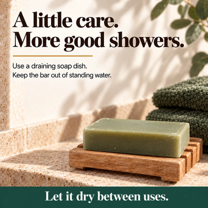 Athlete's Shield soap bar on a draining wooden soap dish beside green towels