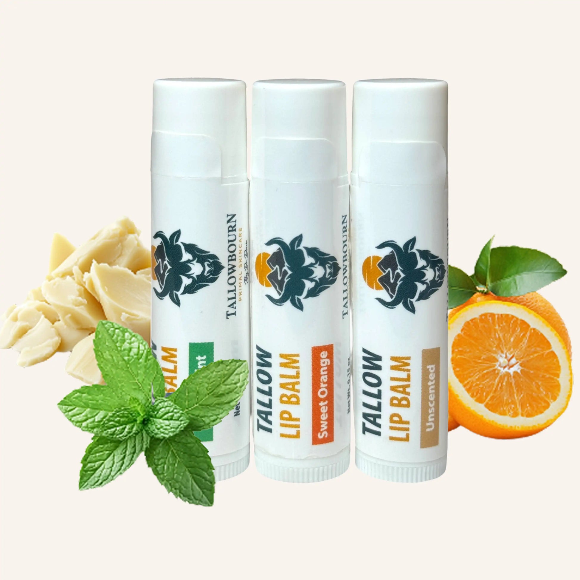 Three assorted tallowbourn lip balm tubes with different flavors and a slice of orange on a white background