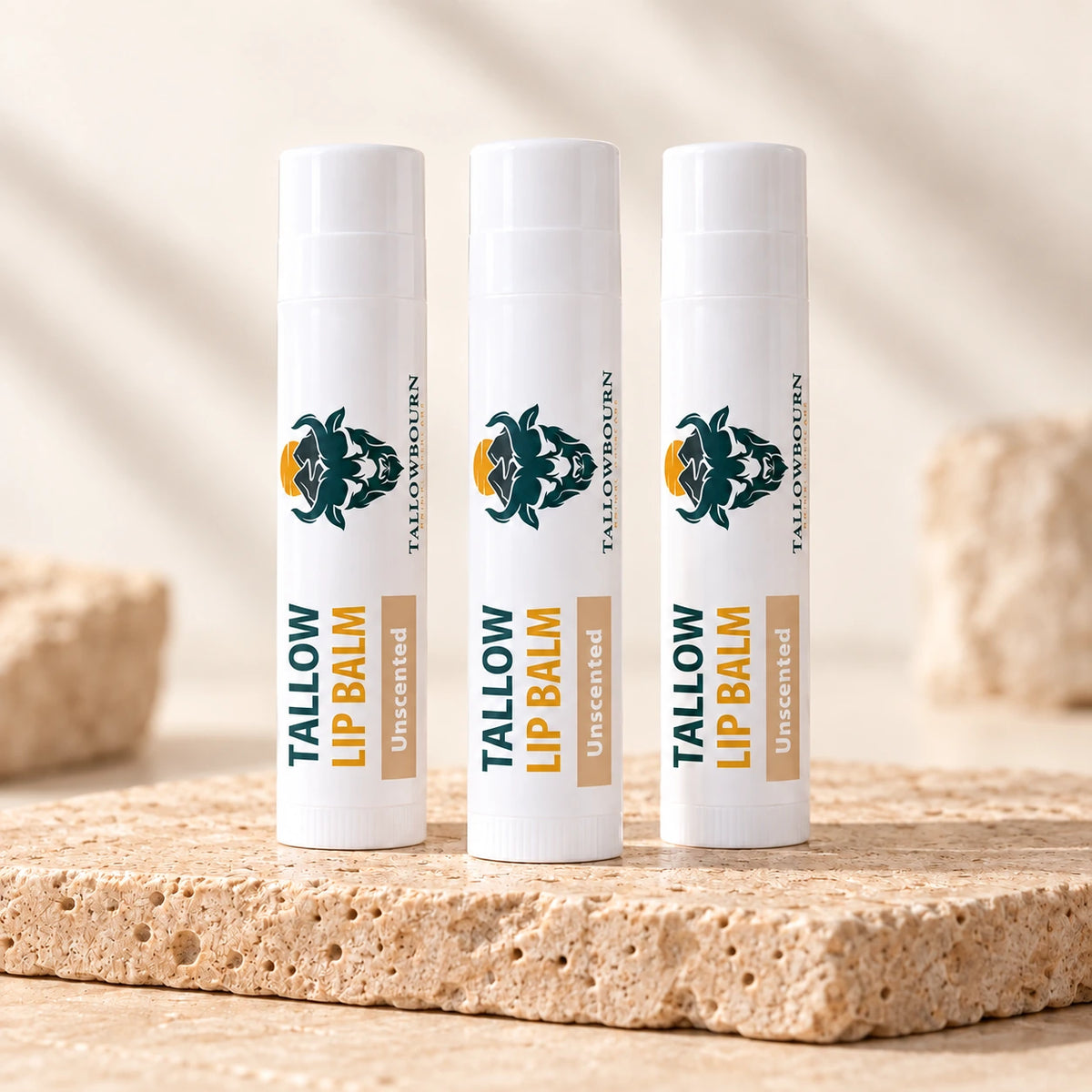 Three Unscented Tallow Lip Balm tubes standing on a stone slab
