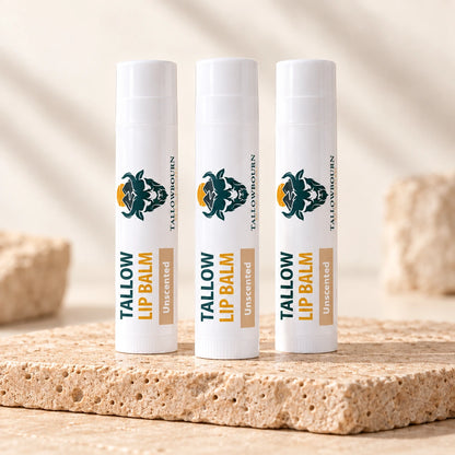 Three Unscented Tallow Lip Balm tubes standing on a stone slab