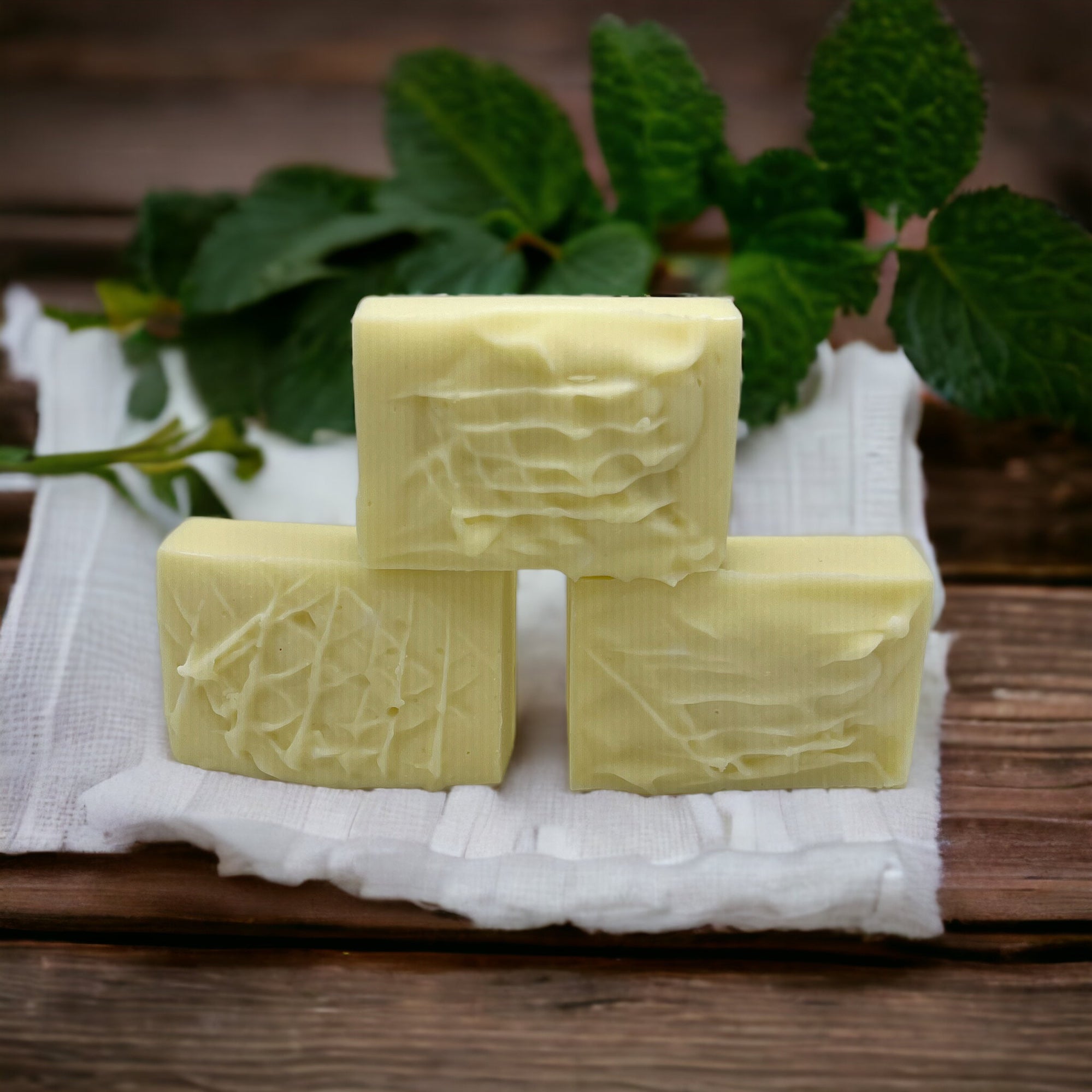 Three handcrafted soap bars stacked with a textured creamy surface.